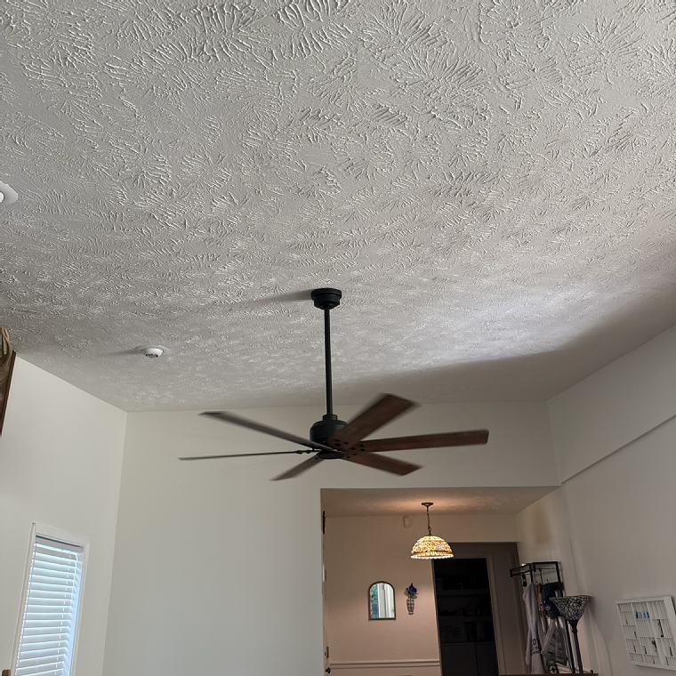 Newly installed ceiling fan on a textured ceiling in a home