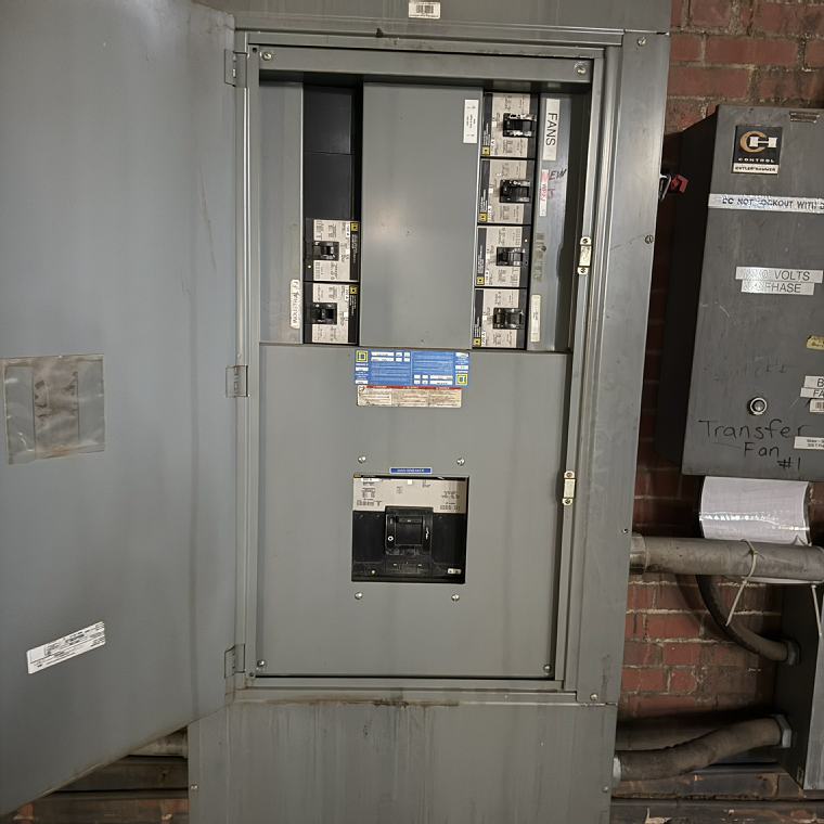 Open 480-volt three-phase panelboard with breakers feeding industrial fans
