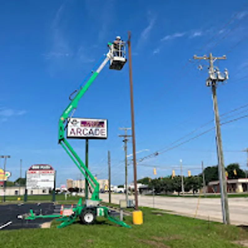 Electrician in a towable boom lift working at a tall pylon sign in a commercial plaza