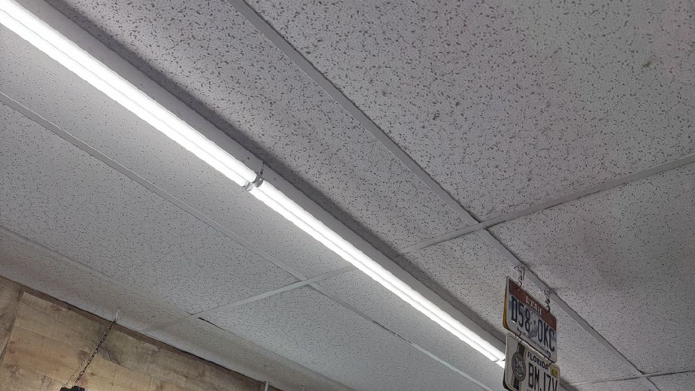 Newly installed LED tube fixtures in the suspended ceiling grid of a commercial tenant space